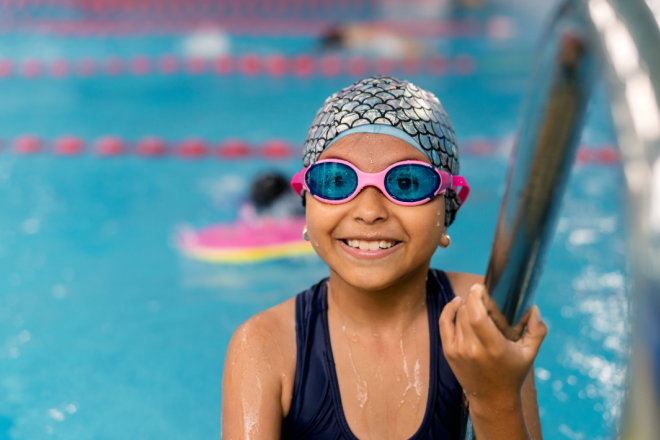 Meisje kijkt in camera tijdens haar zwemles