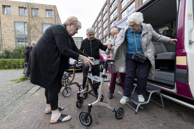 Vrijwilliger van de BBD helpt oudere uit de bus te stappen