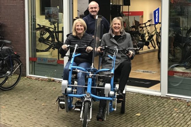 Op de gloednieuwe duofiets van Fietsmaatjes, met Ingrid links op de fiets. Ook op foto staan Ellen Klompé, voorzitter van Fietsmaatjes Wassenaar, en de eigenaar van fietsspecialist Besuyen in Voorschoten.