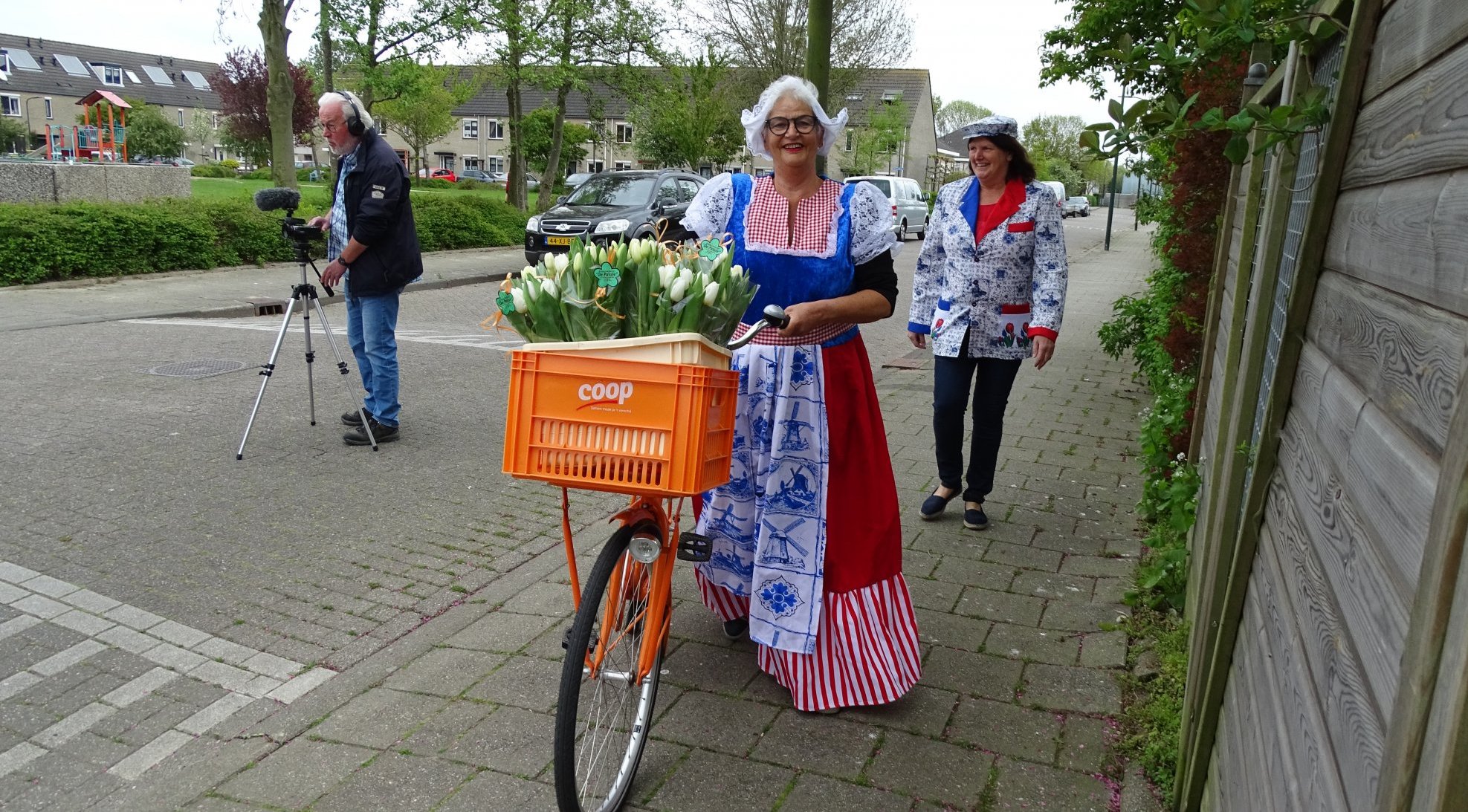 Stompwijk in beweging: Petra deelt bloemen uit aan buurtbewoners. Op de achtergrond cameraman Jacques van Herten en mede-initiatiefnemer Jokelien van Rijn.