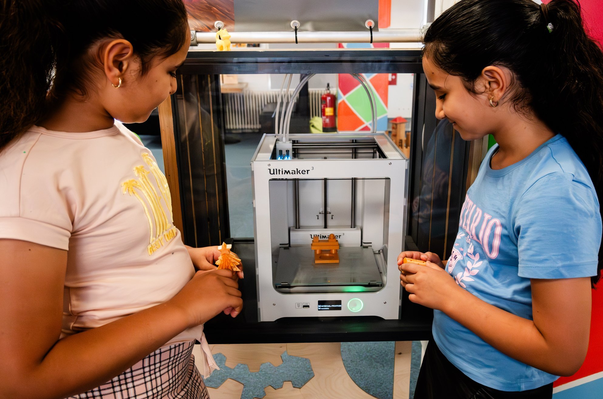 Twee meisjes kijken naar een 3D-printer in de digiruimte in de bibliotheek Katwijk