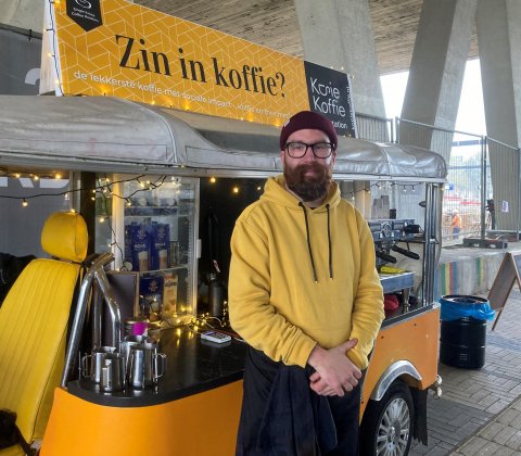 Raymond poseert voor zijn koffiekar op station Delft Campus